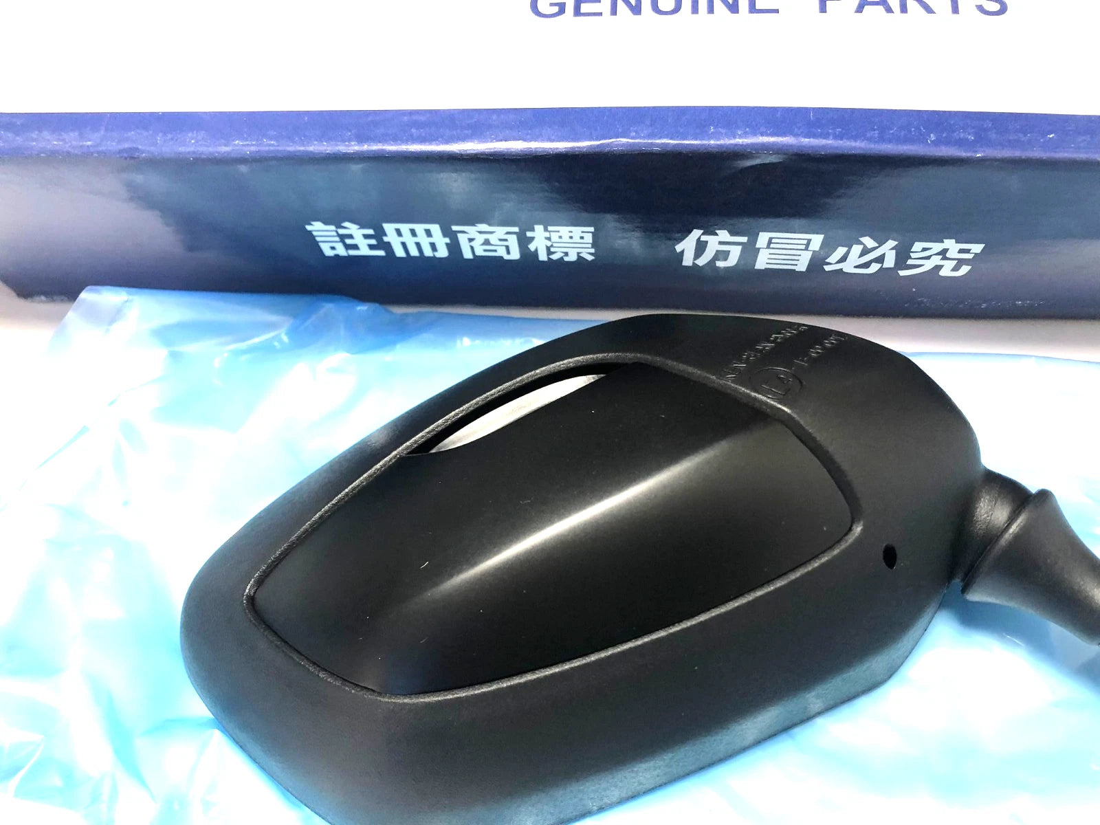 Black plastic mirror part with visible Chinese text “OEM Parts” and “300 RH” on a blue box.